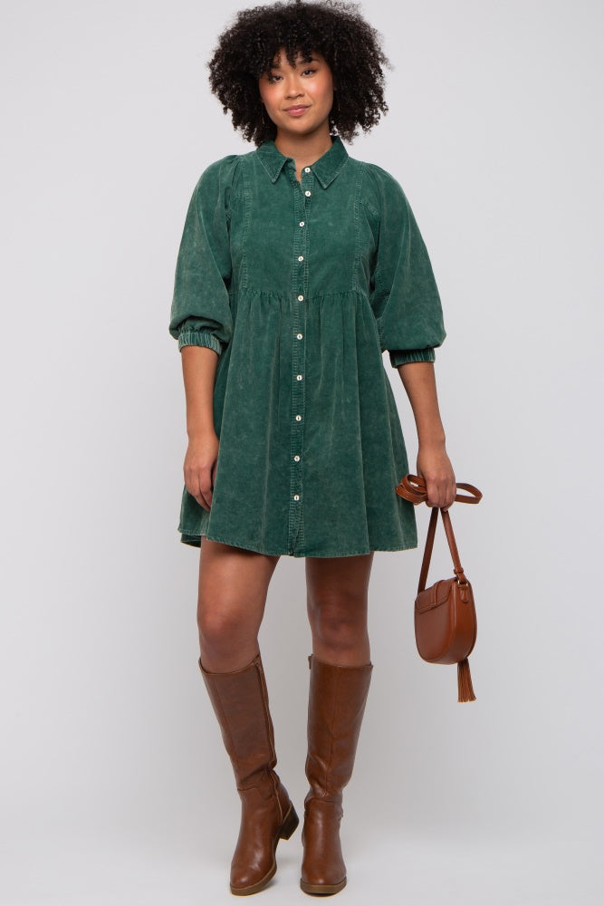 woman wearing a green corduroy shirt dress with balloon sleeves and brown knee-high boots, holding a small brown handbag