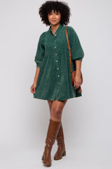 woman wearing a green corduroy shirt dress with puffed sleeves and knee-high brown boots