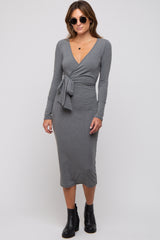 woman wearing a gray long sleeve wrap dress with a tie at the waist and black ankle boots