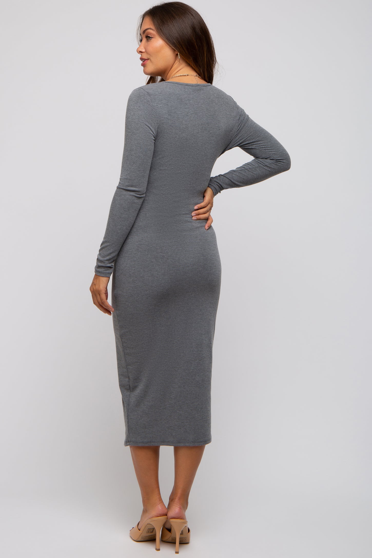 woman wearing a fitted gray long sleeve maternity dress with a midi length and side slit, showing her silhouette
