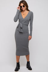 woman wearing a grey long sleeve wrap dress with a tie at the waist and black ankle boots
