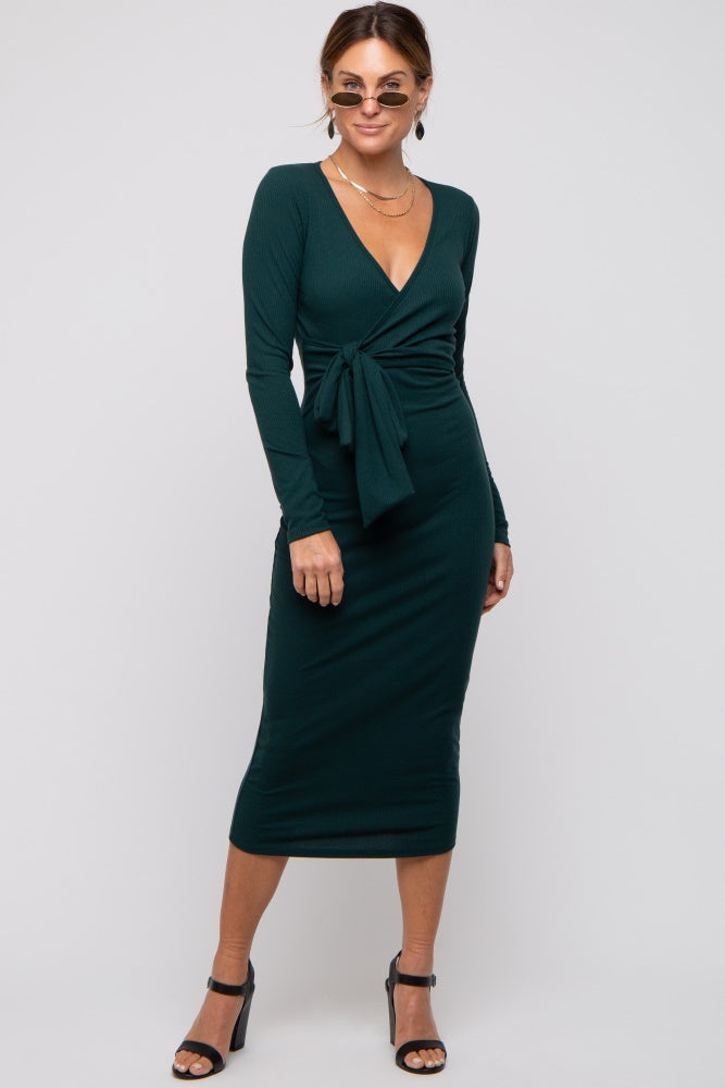 woman wearing a dark green fitted midi dress with long sleeves and a front tie detail, styled with sunglasses and heels
