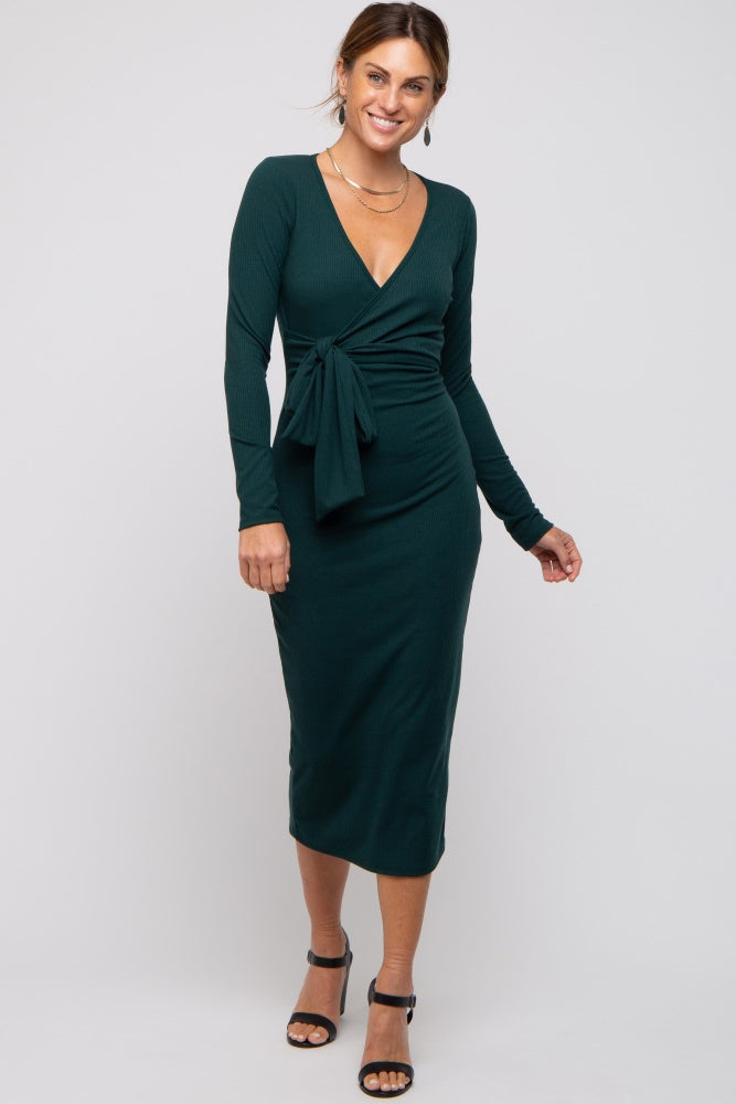 woman wearing a dark green long sleeve wrap dress with a tie detail and a fitted silhouette