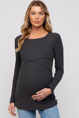 woman wearing a dark gray ribbed maternity top and gently holding her baby bump