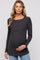 woman wearing a dark gray ribbed maternity top and gently holding her baby bump