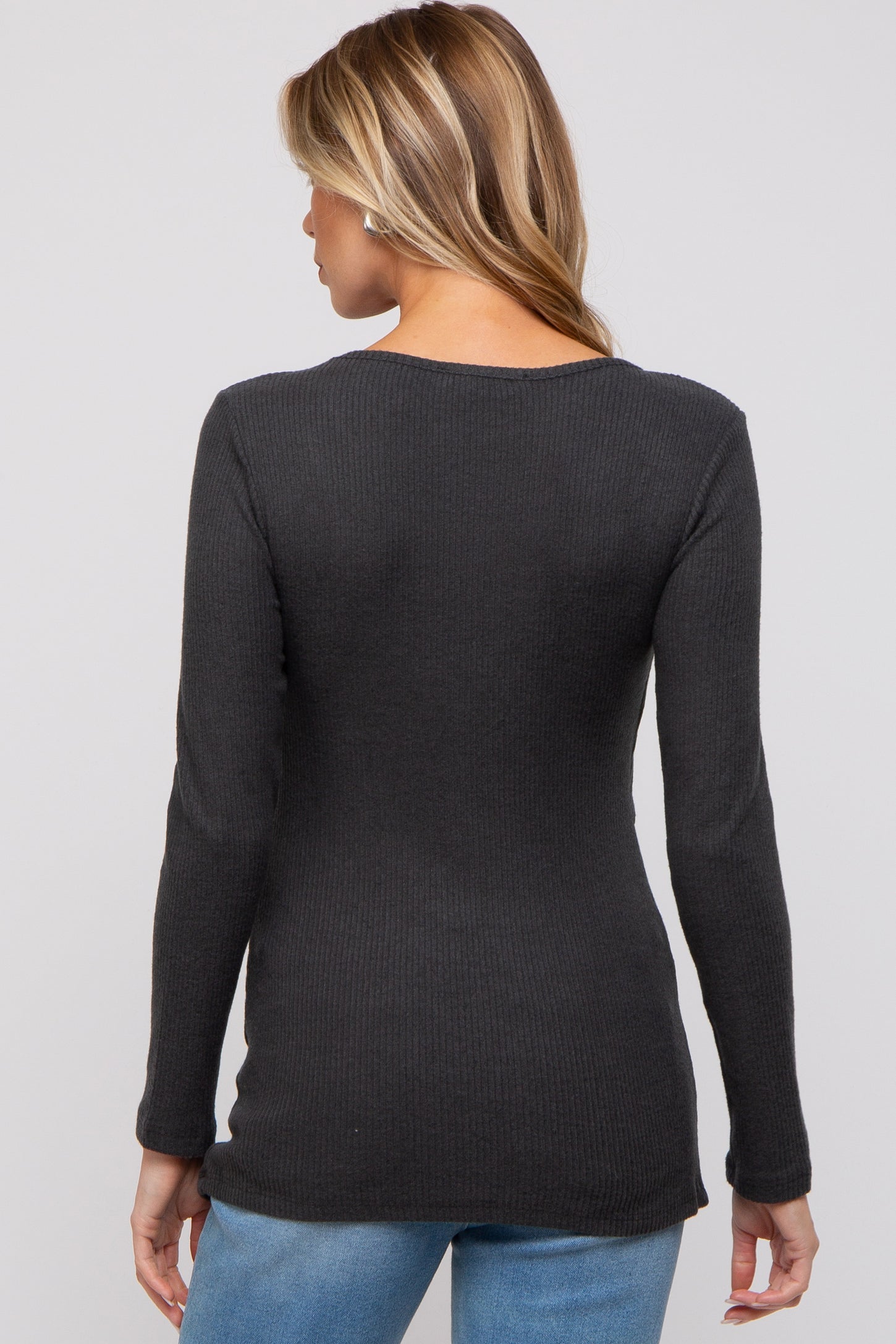woman wearing a dark gray ribbed maternity top, showing the back view, paired with blue jeans