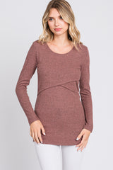 woman wearing a rust ribbed long sleeve top with a twist detail at the waist and white jeans