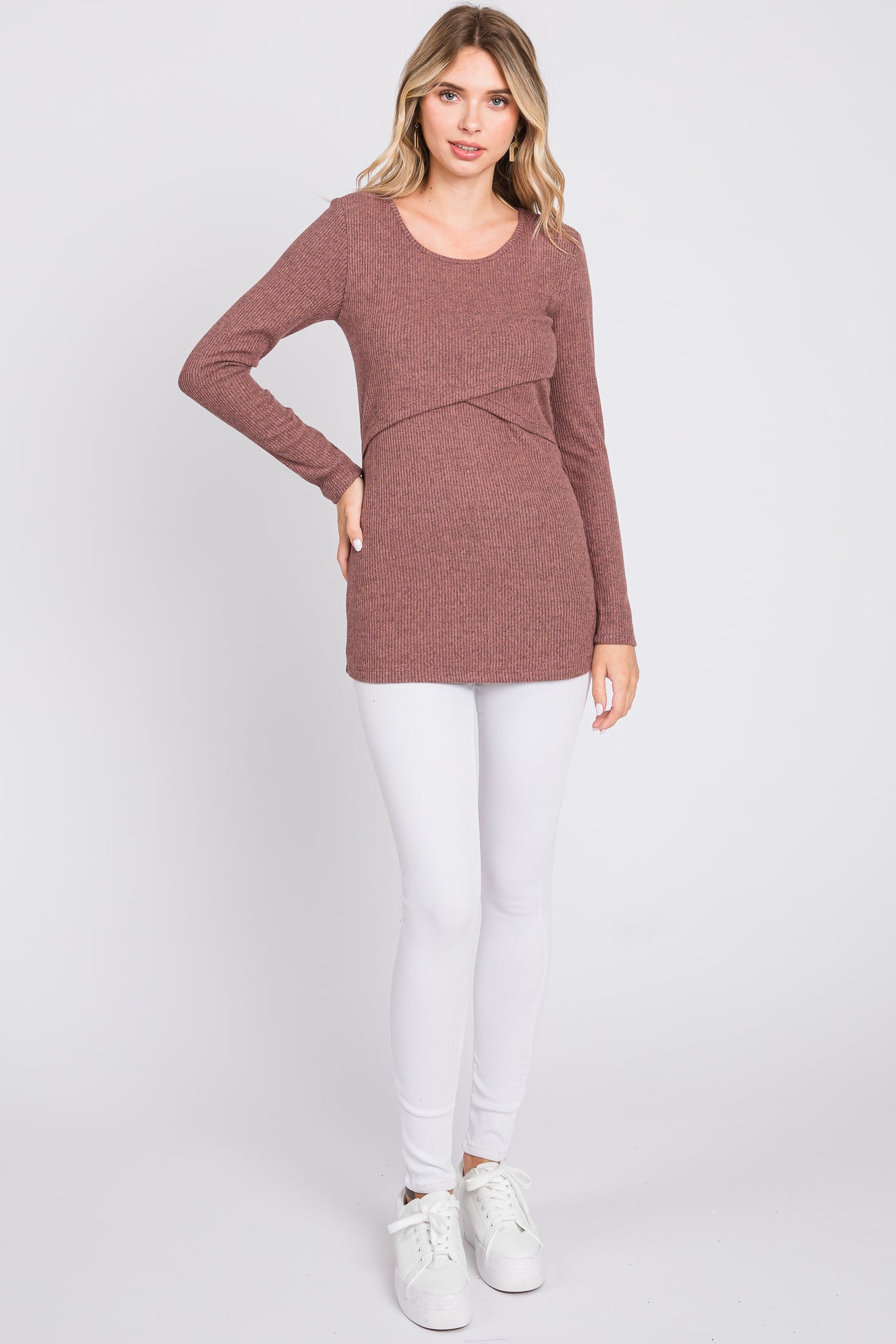 woman wearing a rust ribbed long sleeve top with a crossover design, paired with white leggings and white sneakers