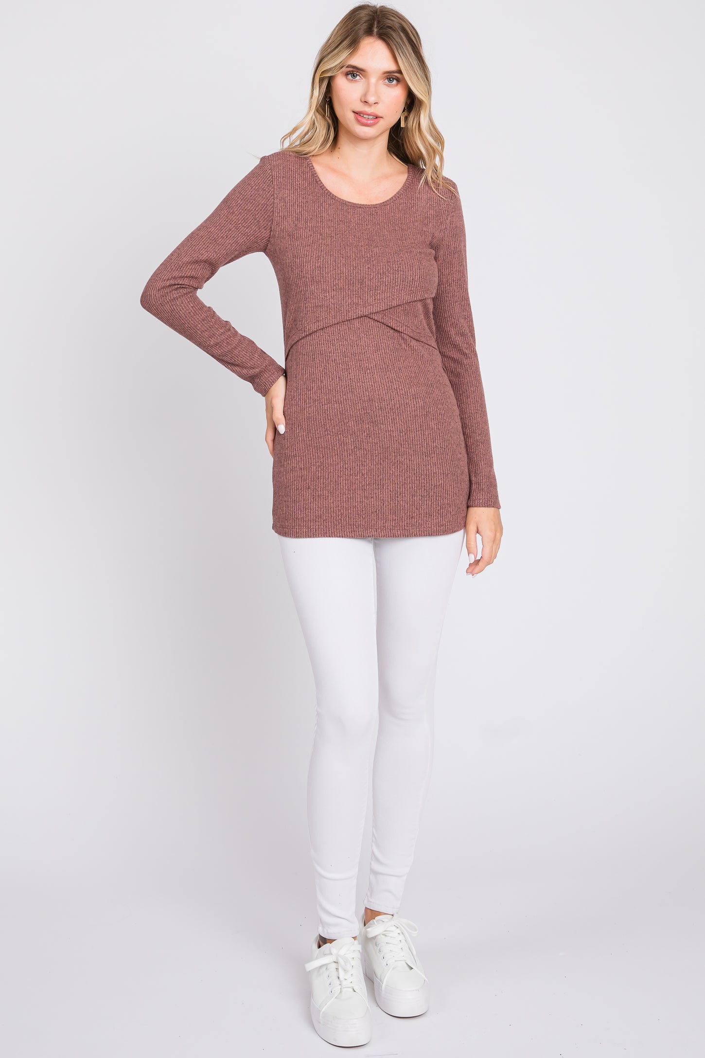 woman wearing a rust ribbed long sleeve top with a crossover design, paired with white leggings and white sneakers