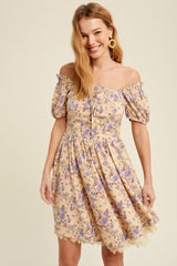 woman wearing a yellow off-shoulder floral dress with puff sleeves and a lace hem, smiling at the camera