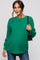 woman wearing a green oversized knit maternity sweater and holding a black handbag, baby bump visible