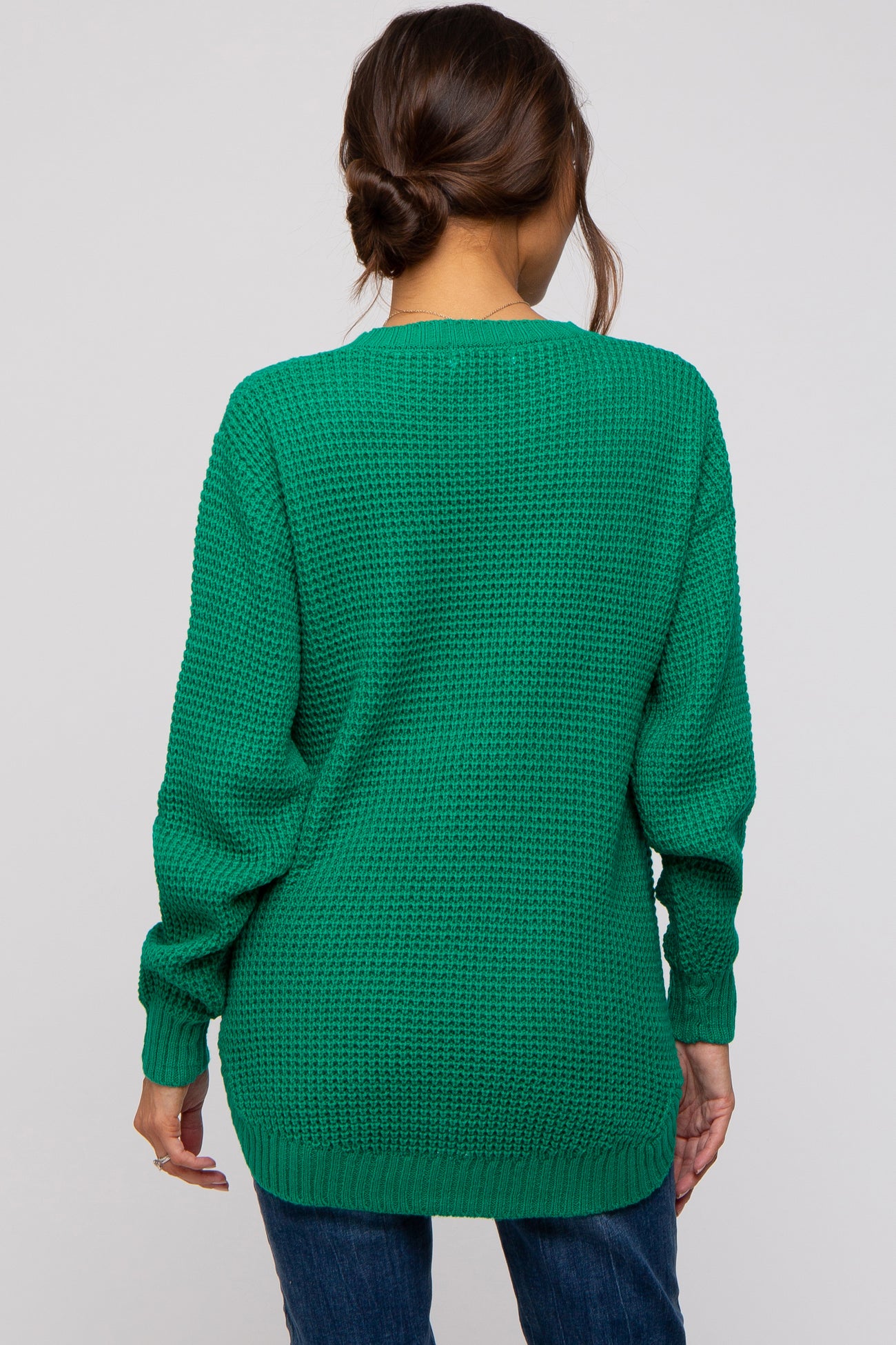woman wearing a green oversized knit maternity sweater, styled with a relaxed fit and long sleeves