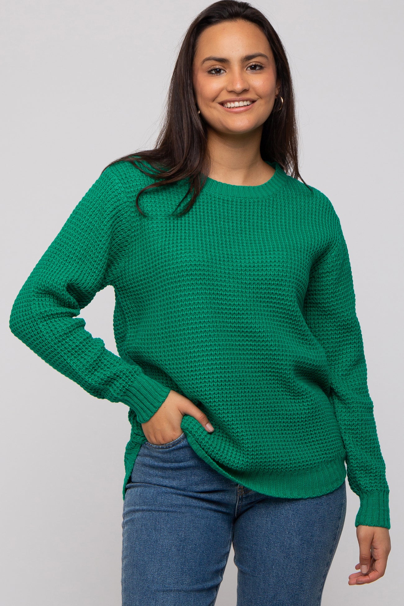 woman wearing a green textured sweater with long sleeves and a relaxed fit, styled with blue jeans