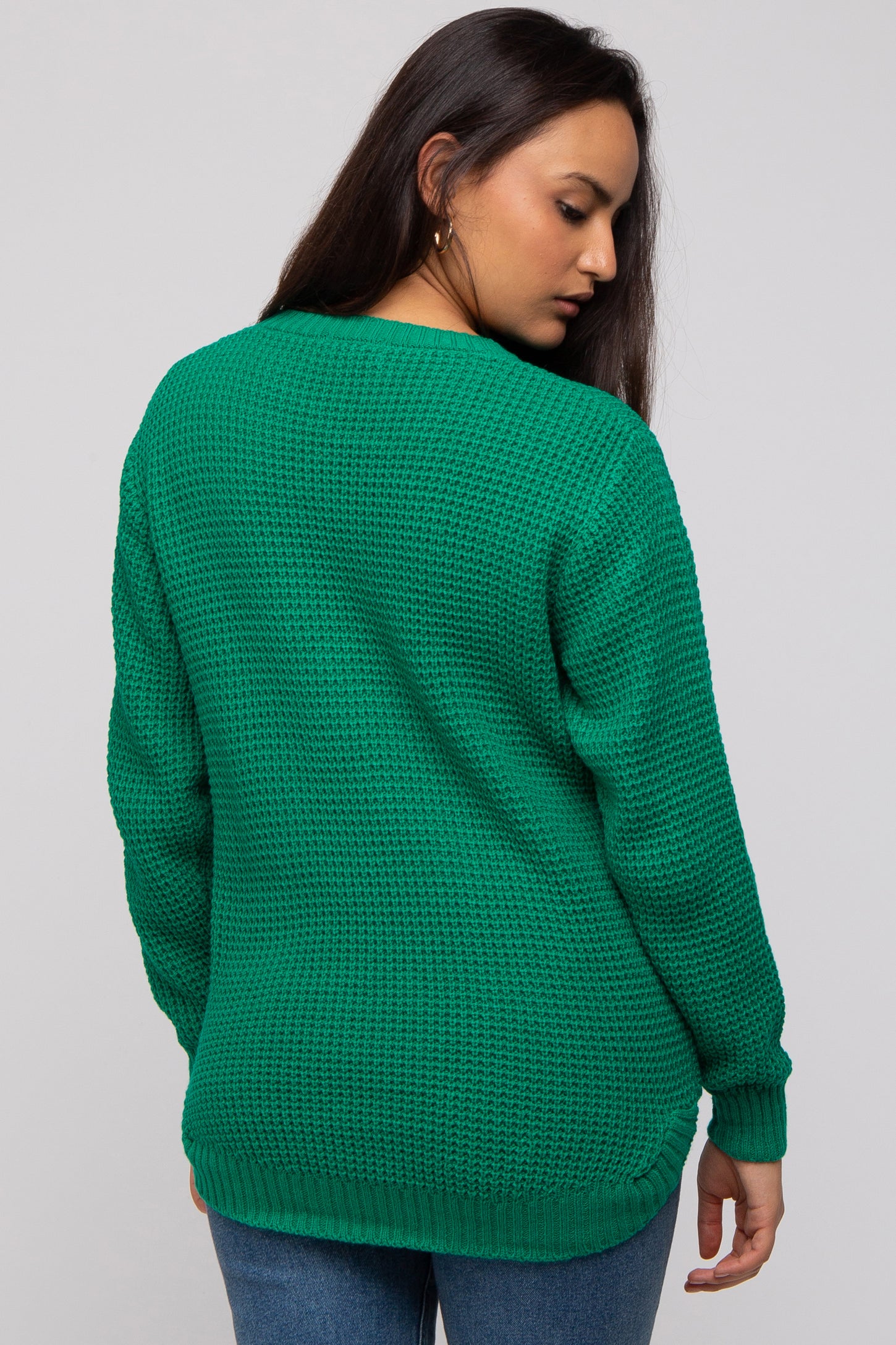 woman wearing a green knit sweater with a relaxed fit and ribbed cuffs, viewed from the back