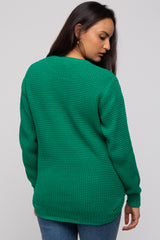 woman wearing a green knit sweater with a relaxed fit and ribbed cuffs, viewed from the back