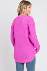 woman wearing a bright pink chunky knit sweater with a slightly longer back and relaxed fit, paired with jeans