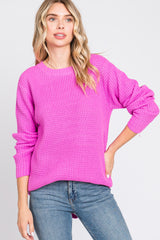 woman wearing a bright pink knit sweater with long sleeves and a relaxed fit, paired with blue jeans