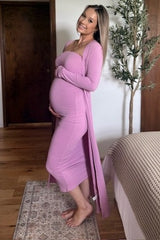 woman wearing a pink ribbed maternity dress and long cardigan, gently cradling her baby bump