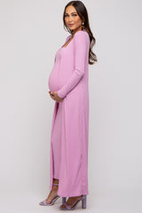 woman wearing a pink ribbed maternity dress with long sleeves and a thigh-high slit, showcasing her baby bump