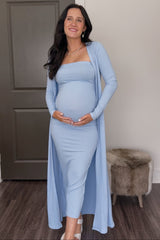 woman wearing a light blue maternity dress with a long cardigan, showing her baby bump