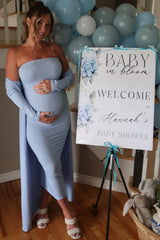 woman wearing a light blue ribbed off-shoulder maternity dress with a side slit and holding her baby bump