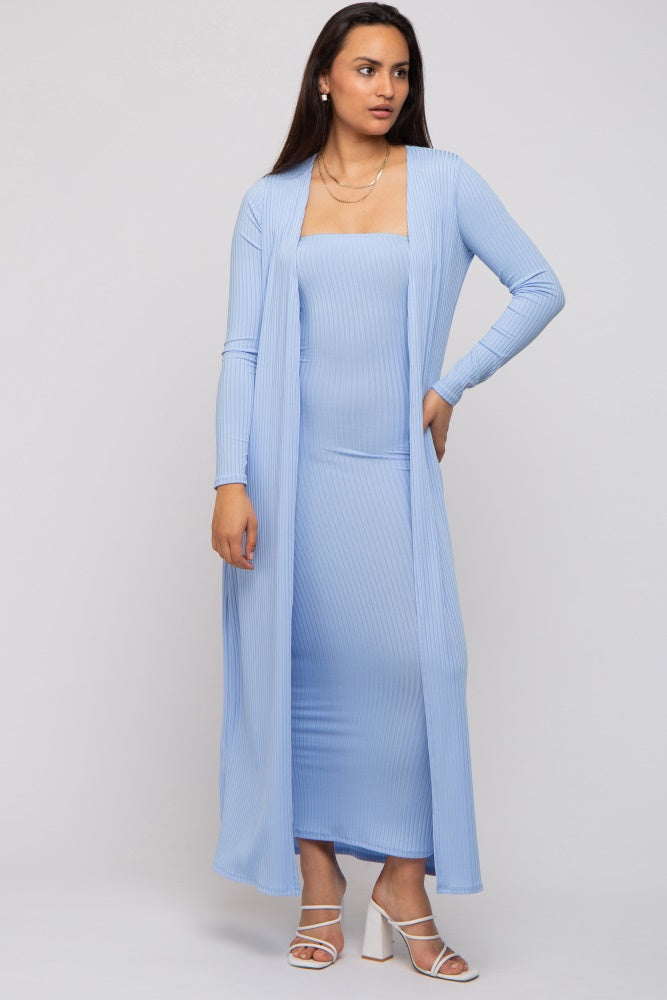 woman wearing a light blue ribbed strapless maxi dress with a matching long cardigan and white strappy heels