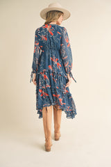 woman wearing a blue floral print maxi dress with long sleeves and ruffle details, paired with knee-high tan boots