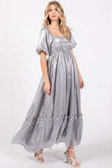 woman wearing a silver maxi dress with puff sleeves and a tiered hemline