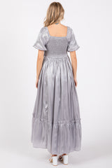 woman wearing a silver satin maxi dress with puff sleeves and a smocked bodice, shown from the back