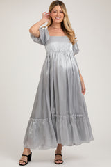 woman wearing a silver satin maternity maxi dress with puff sleeves and ruffled hem