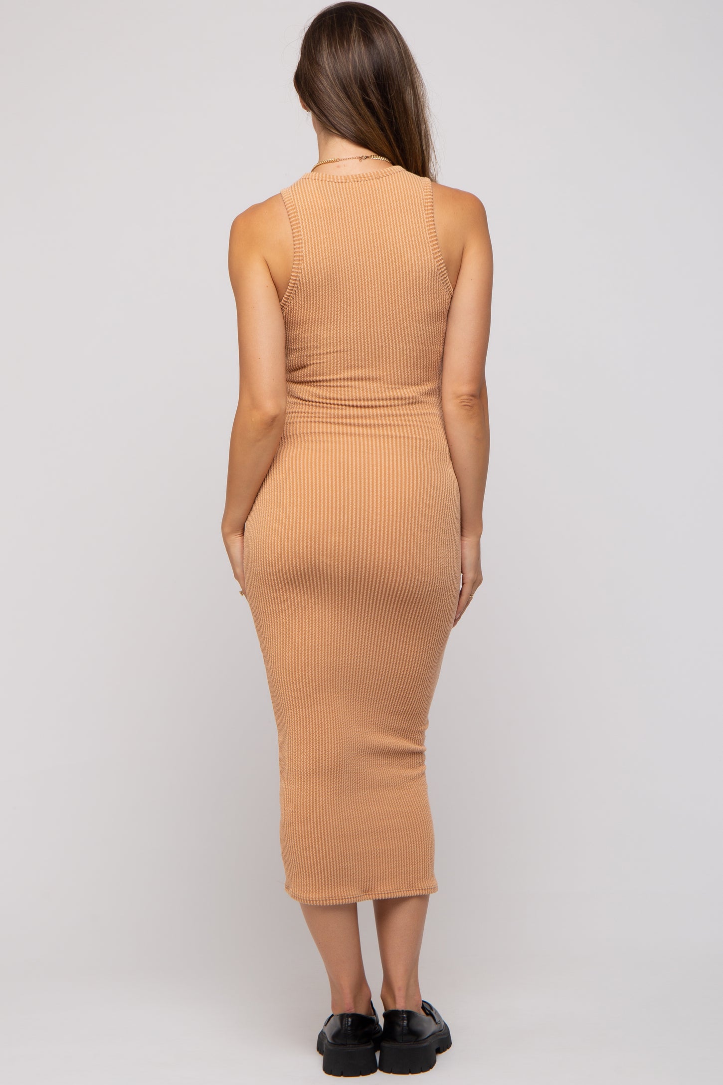 woman wearing a form-fitting ribbed midi maternity dress in a warm terracotta color, viewed from the back