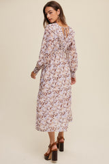 woman wearing a long-sleeve floral midi dress with a ruffled neckline and back ties, showing a relaxed fit and soft colors