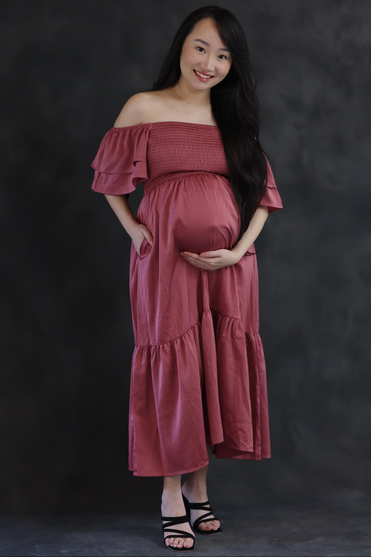 woman wearing a dusty rose off-the-shoulder maternity dress with ruffle sleeves and a visible baby bump