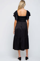 woman wearing a black maternity dress with ruffled sleeves and a tiered skirt, view from the back