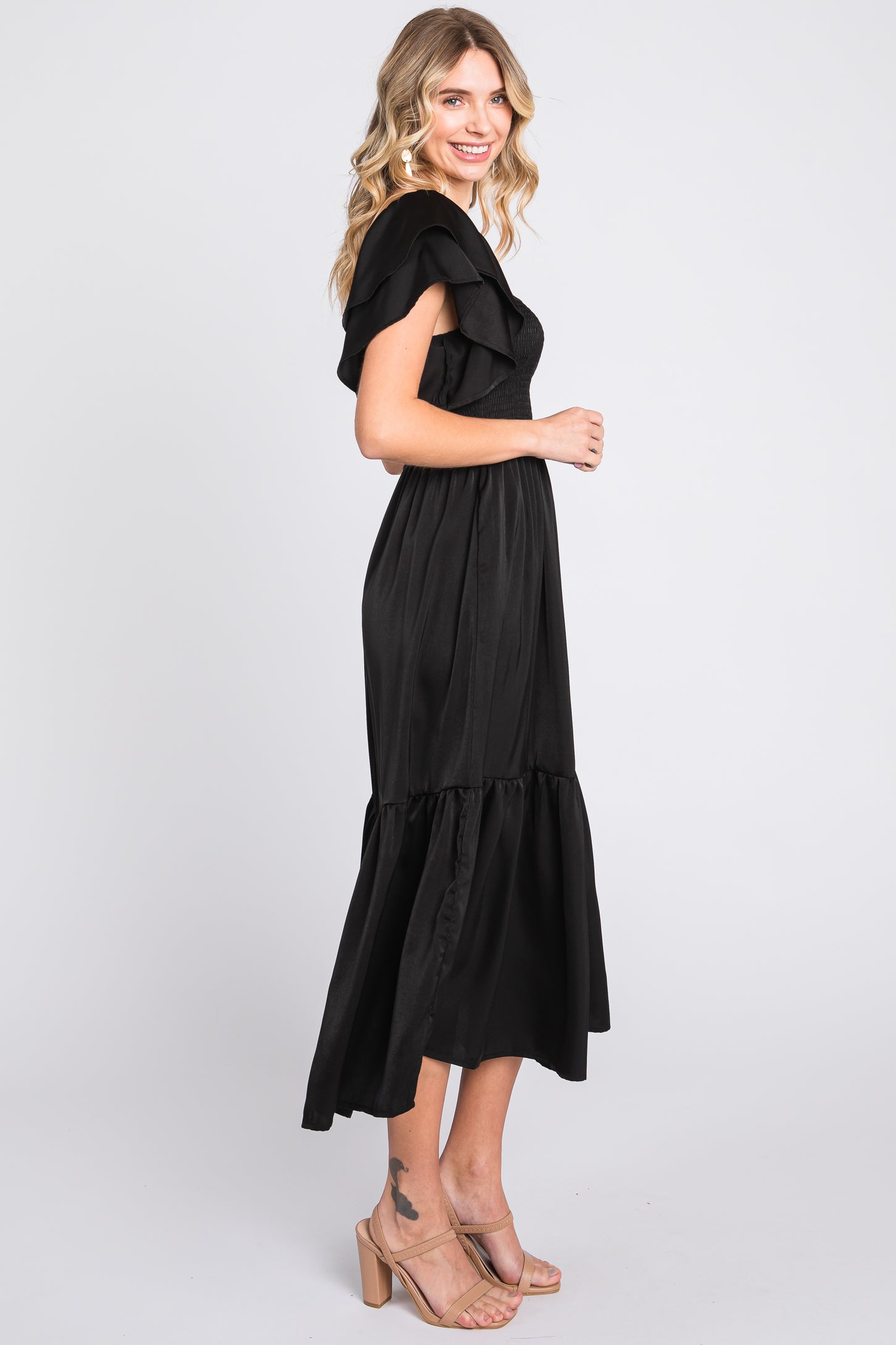 woman wearing a black off-the-shoulder maxi dress with ruffle details and a tiered skirt