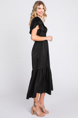 woman wearing a black off-the-shoulder maxi dress with ruffle details and a tiered skirt
