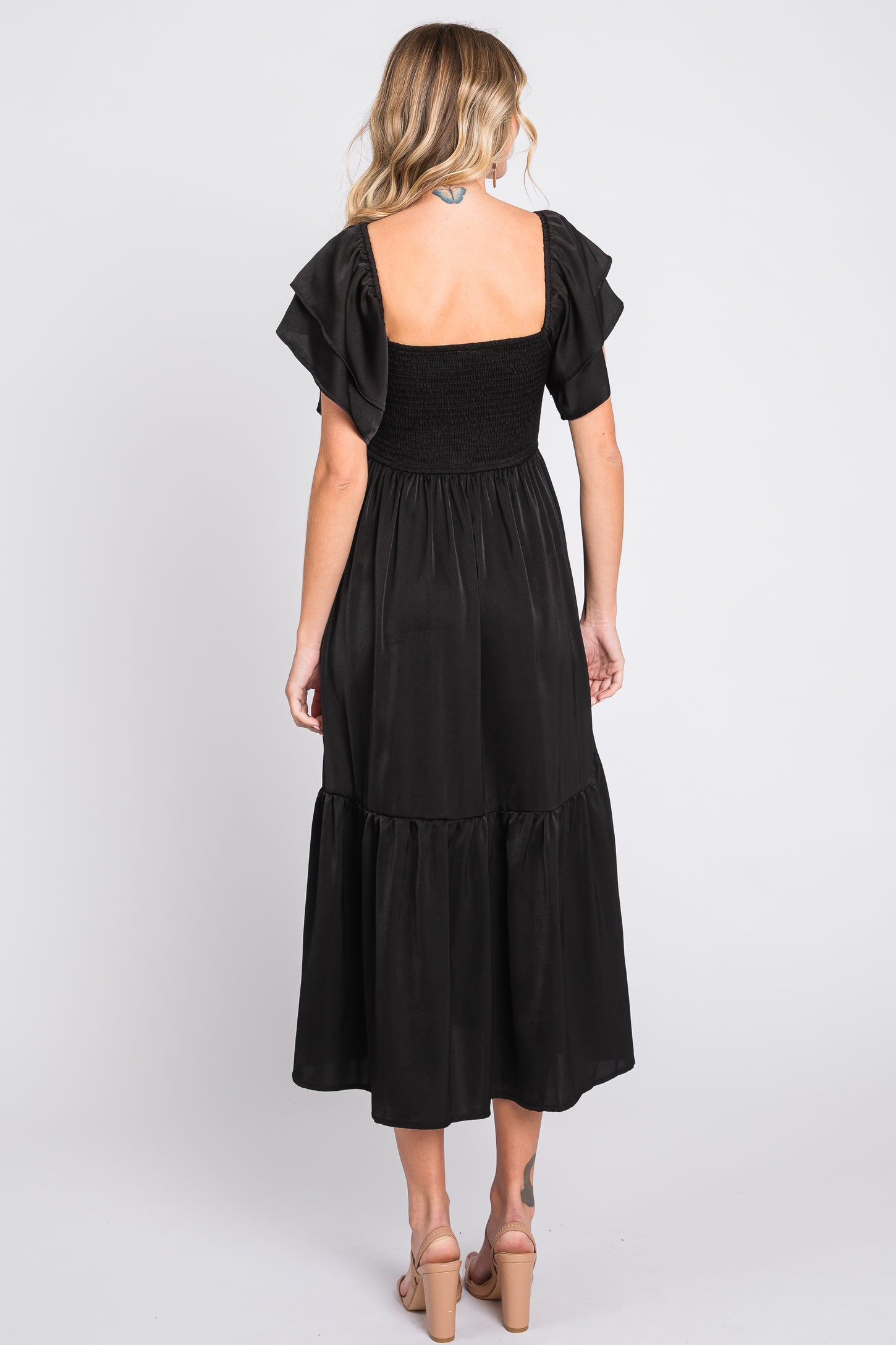 woman wearing a black tiered maxi dress with a smocked bodice and flutter sleeves, shown from the back