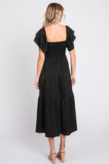 woman wearing a black tiered maxi dress with a smocked bodice and flutter sleeves, shown from the back