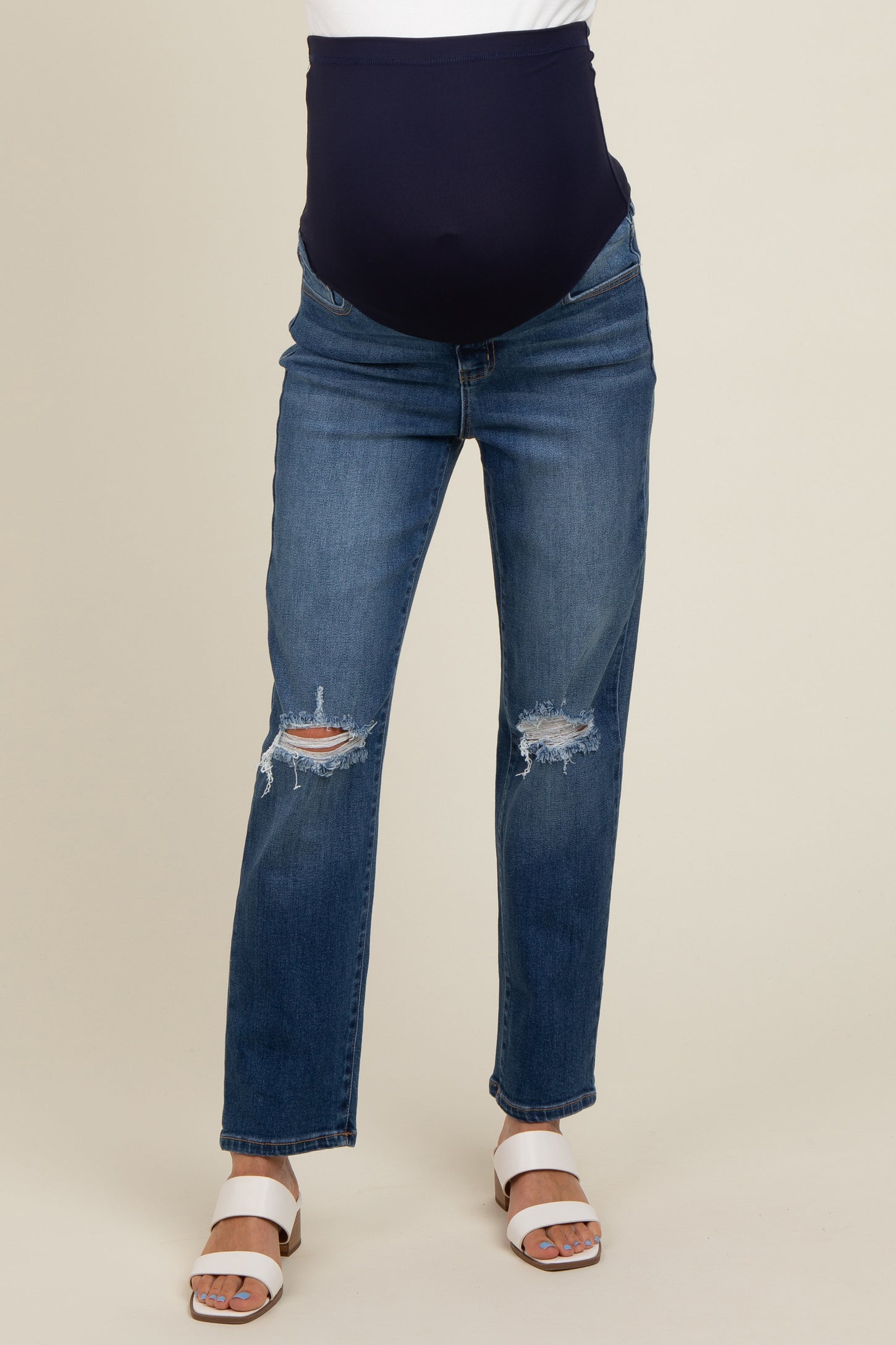 maternity wear blue distressed skinny jeans with a black over-the-bump waistband and worn by a model