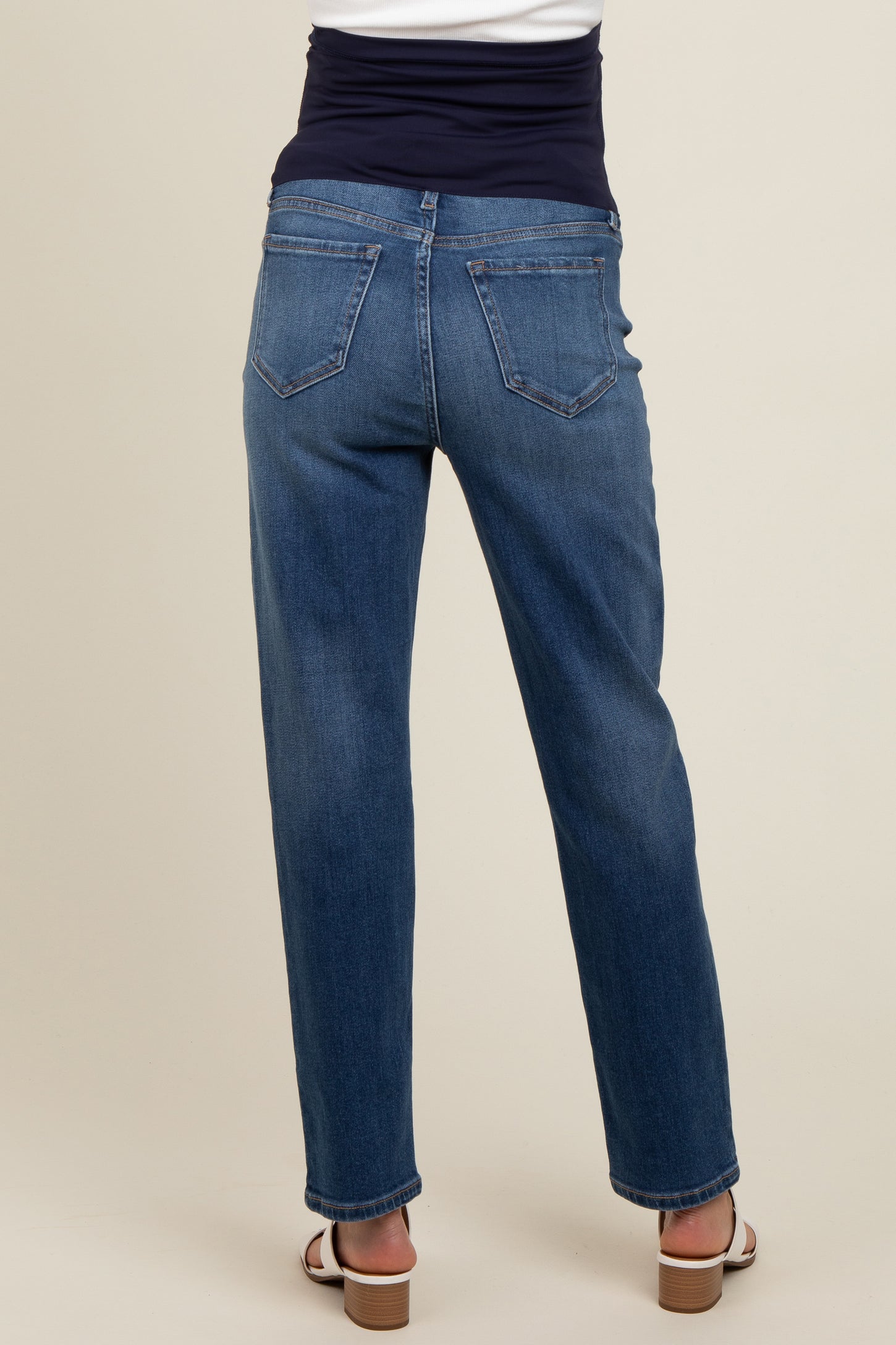 woman wearing a dark blue pair of maternity jeans, showing the back view with a stretchy waistband