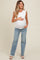 woman wearing a white ruffled sleeve maternity top and blue jeans, showing her baby bump