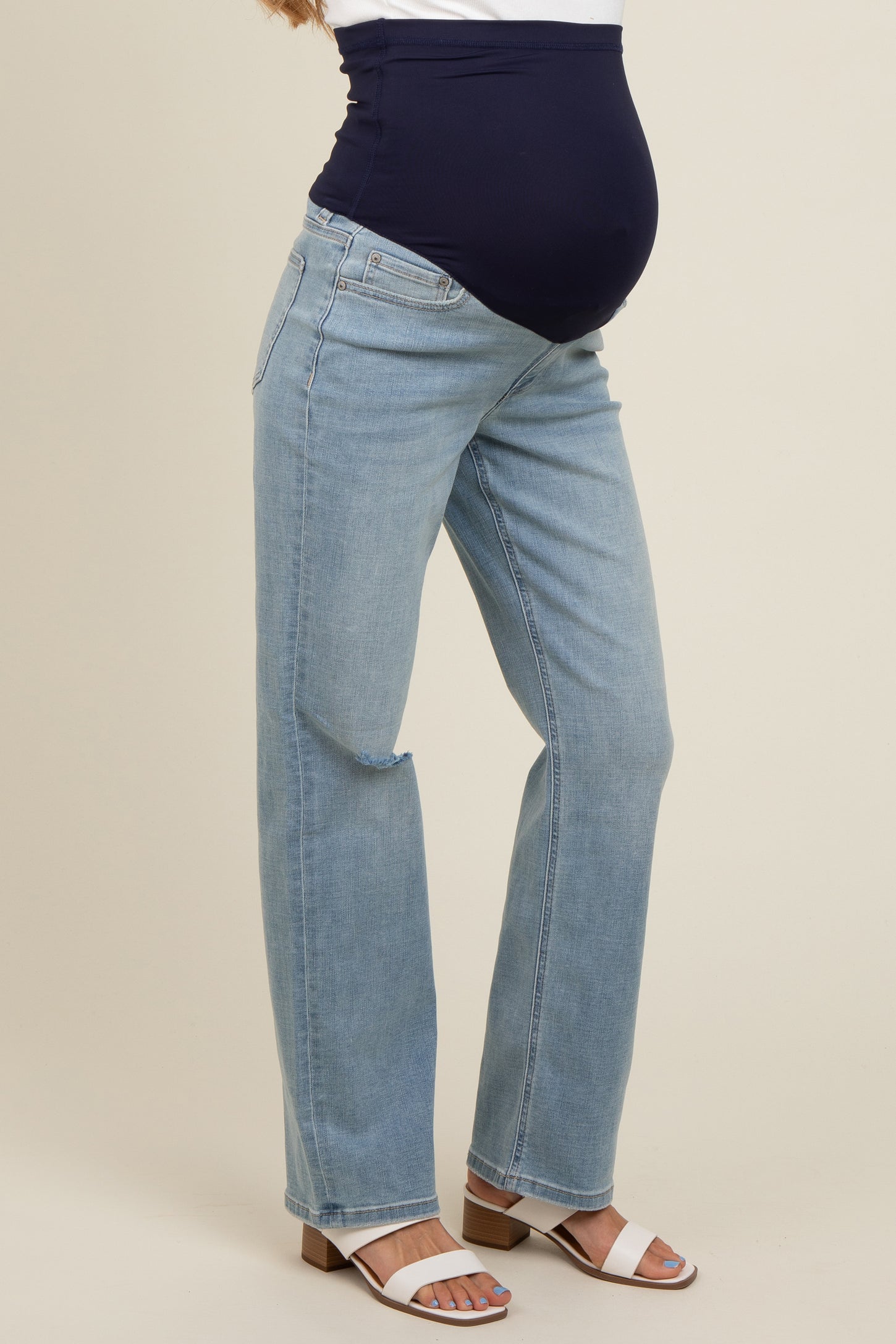 woman wearing light blue maternity jeans with a dark blue belly panel and a visible baby bump