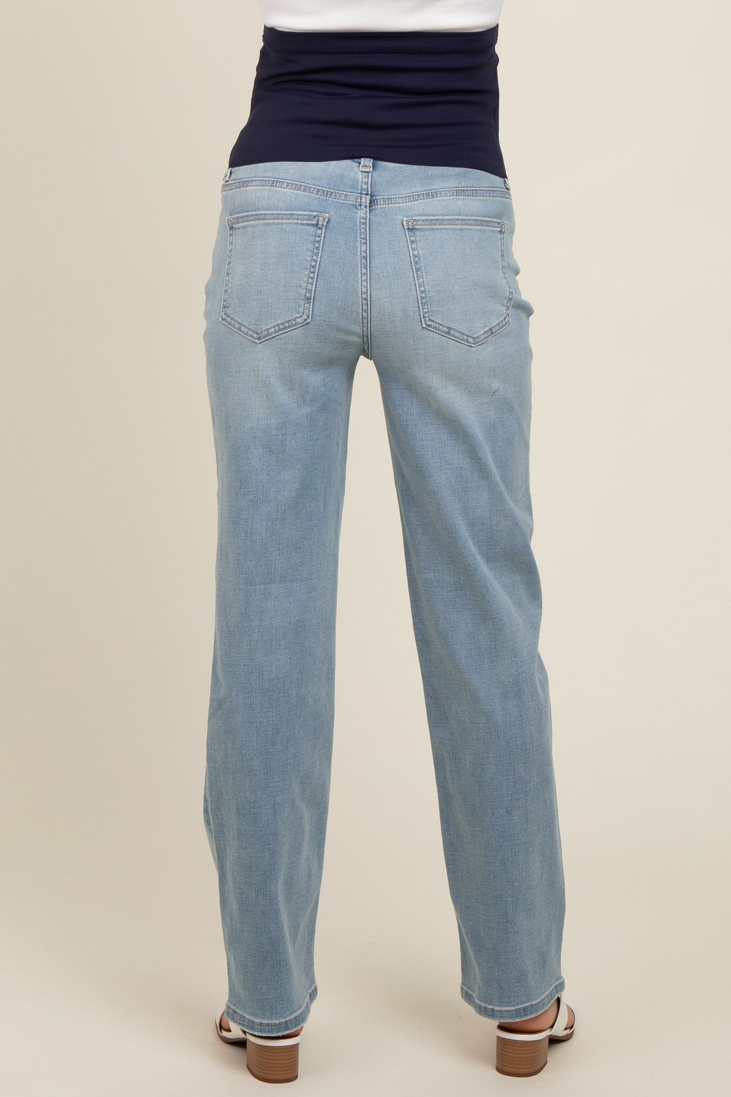 woman wearing light wash maternity jeans viewed from the back, with a comfortable waistband and relaxed fit