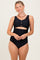 woman wearing a black scalloped cutout swimsuit with button details and high-waisted bottoms
