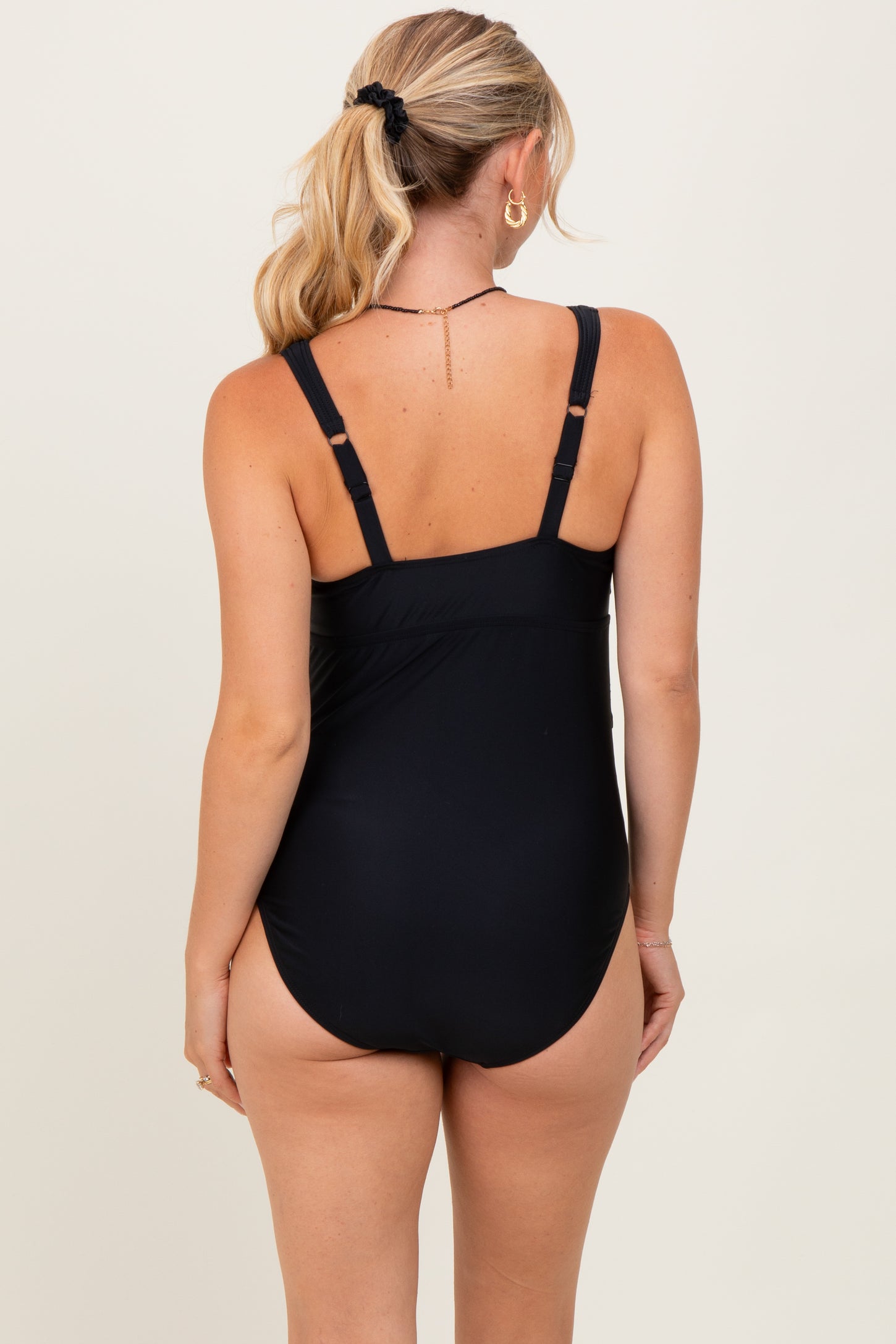 woman wearing a black one-piece swimsuit, showing a low back design and adjustable straps