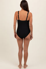 woman wearing a black maternity swimsuit, viewed from the back, featuring adjustable straps