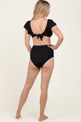 woman wearing a black two-piece bikini with ruffle sleeves and a tied back detail, seen from the back