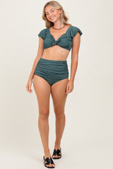 woman wearing a dark green two-piece bikini with flutter sleeves and high-waisted bottoms
