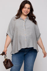 woman wearing a black and white striped maternity plus button-up blouse with rolled sleeves, holding a small handbag