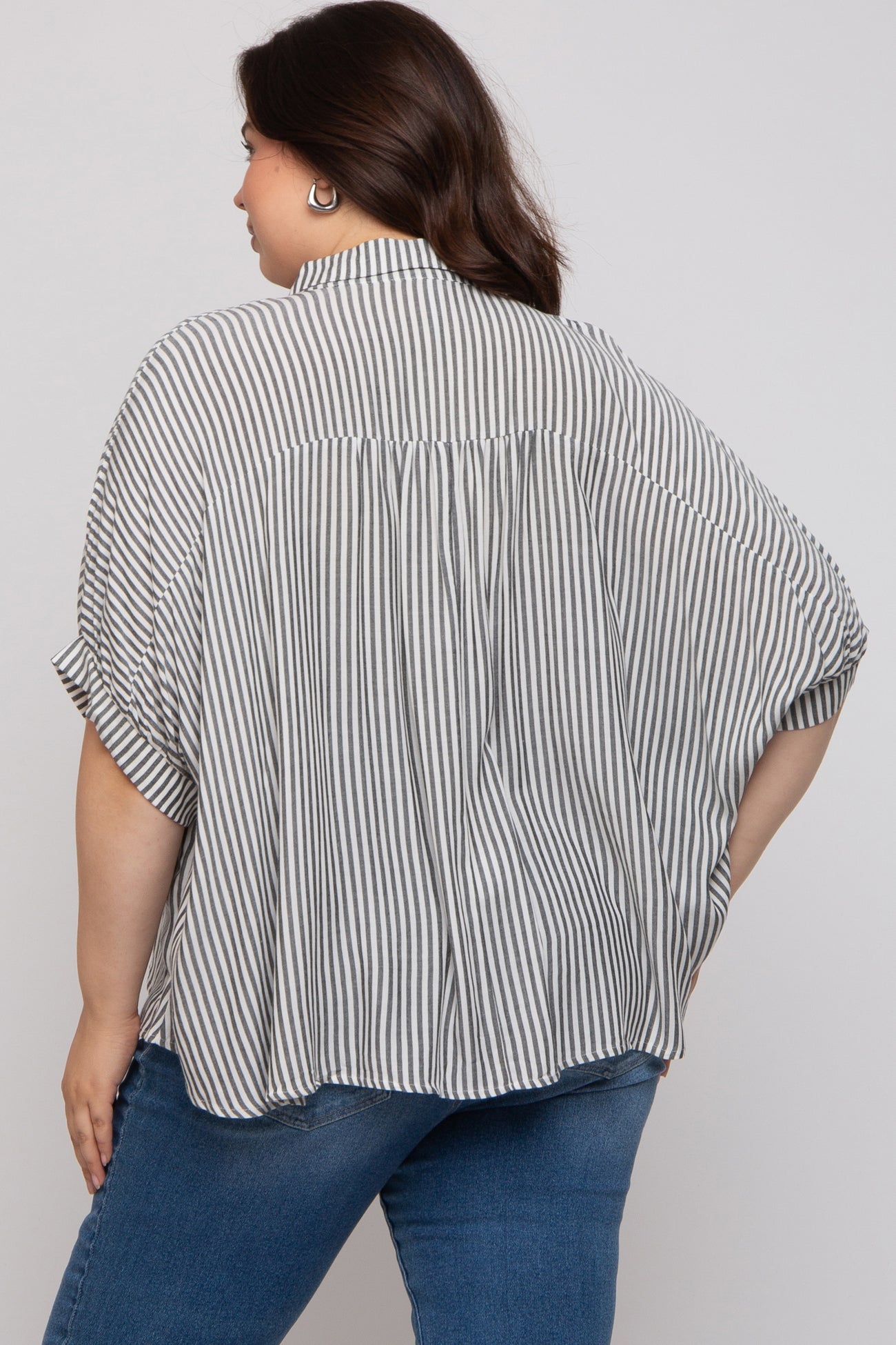 woman wearing a striped black and white maternity plus oversized blouse, showing a relaxed fit and short sleeves